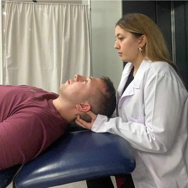 A woman in a lab coat performing a Suboccipital myofascial release technique on a male client.
