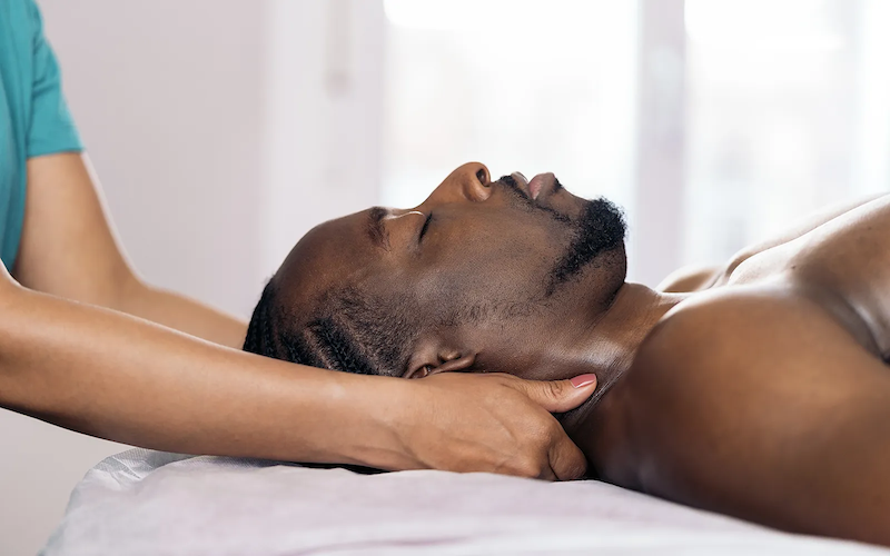 Side view of a practitioner holding an African American man's neck.